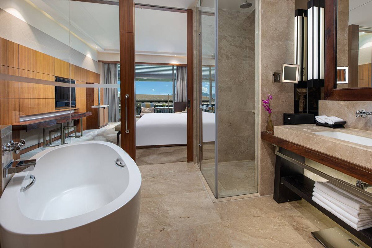 A modern bathroom with a large bathtub, dual sinks, and a shower area.