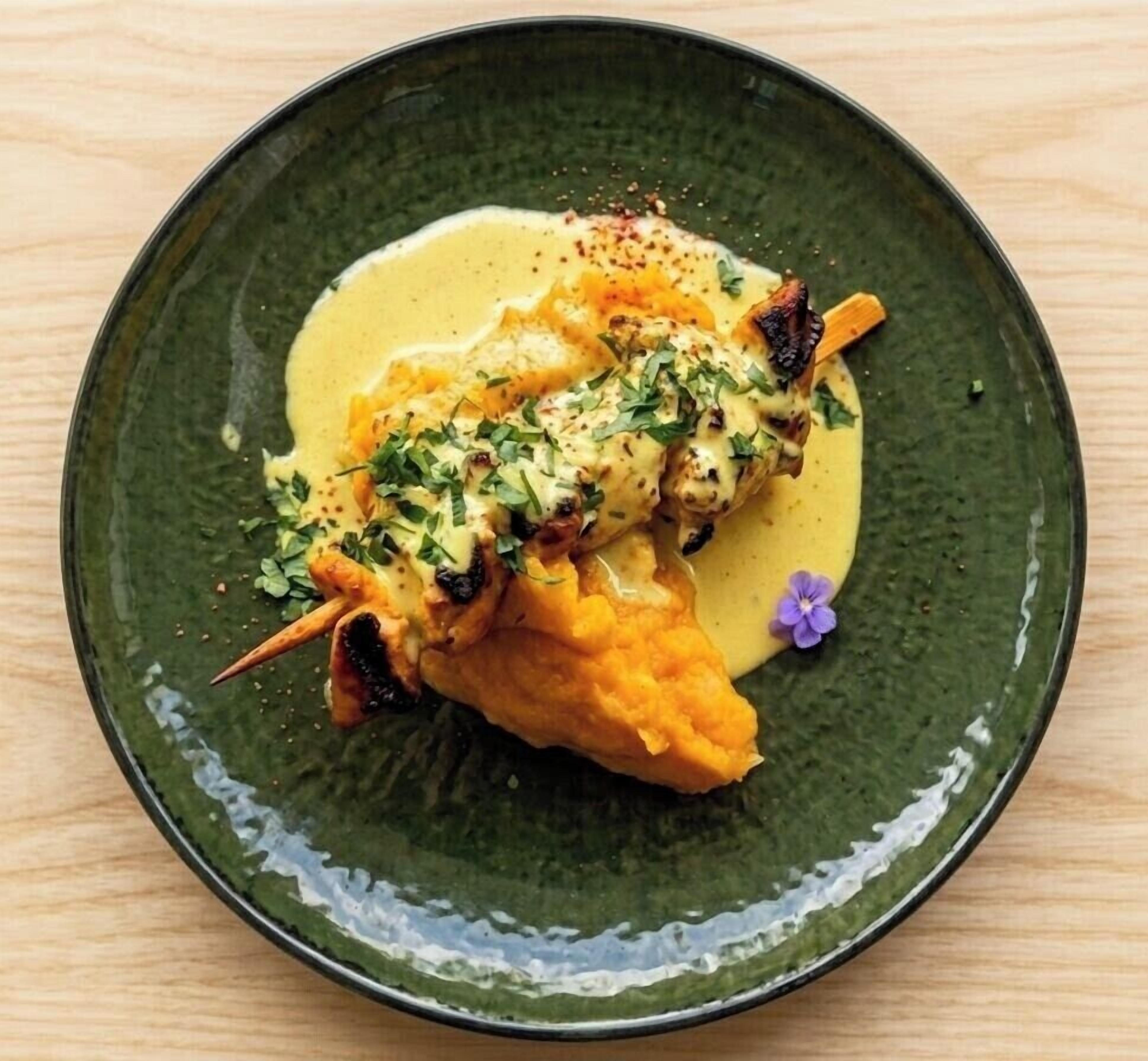 A plate with a food item, possibly a seafood dish, garnished with herbs and a yellow sauce.