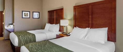 A hotel room with two beds, a nightstand with a lamp, and a small table with a phone.