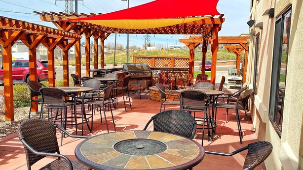An outdoor patio with wicker furniture, a round table, and a barbecue grill.