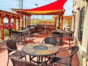 An outdoor patio with wicker furniture, a round table, and a barbecue grill. - Comfort Inn & Suites (Cheyenne)