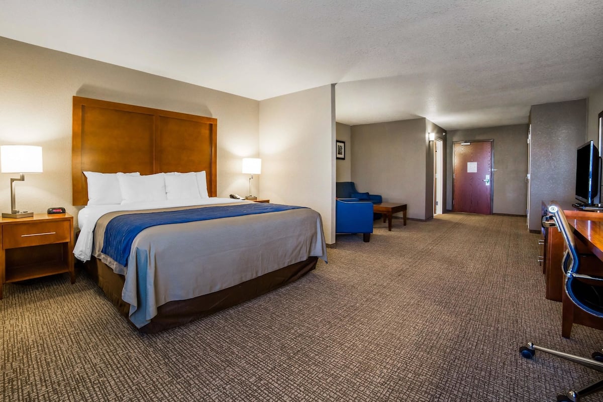 A hotel room with a bed, bedside tables, a desk, a chair, and a television.