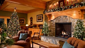 A cozy living room with a fireplace, a Christmas tree, and festive decorations. - Winstead Inn (Harwich)