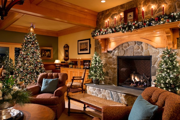 A cozy living room with a fireplace, a Christmas tree, and festive decorations.