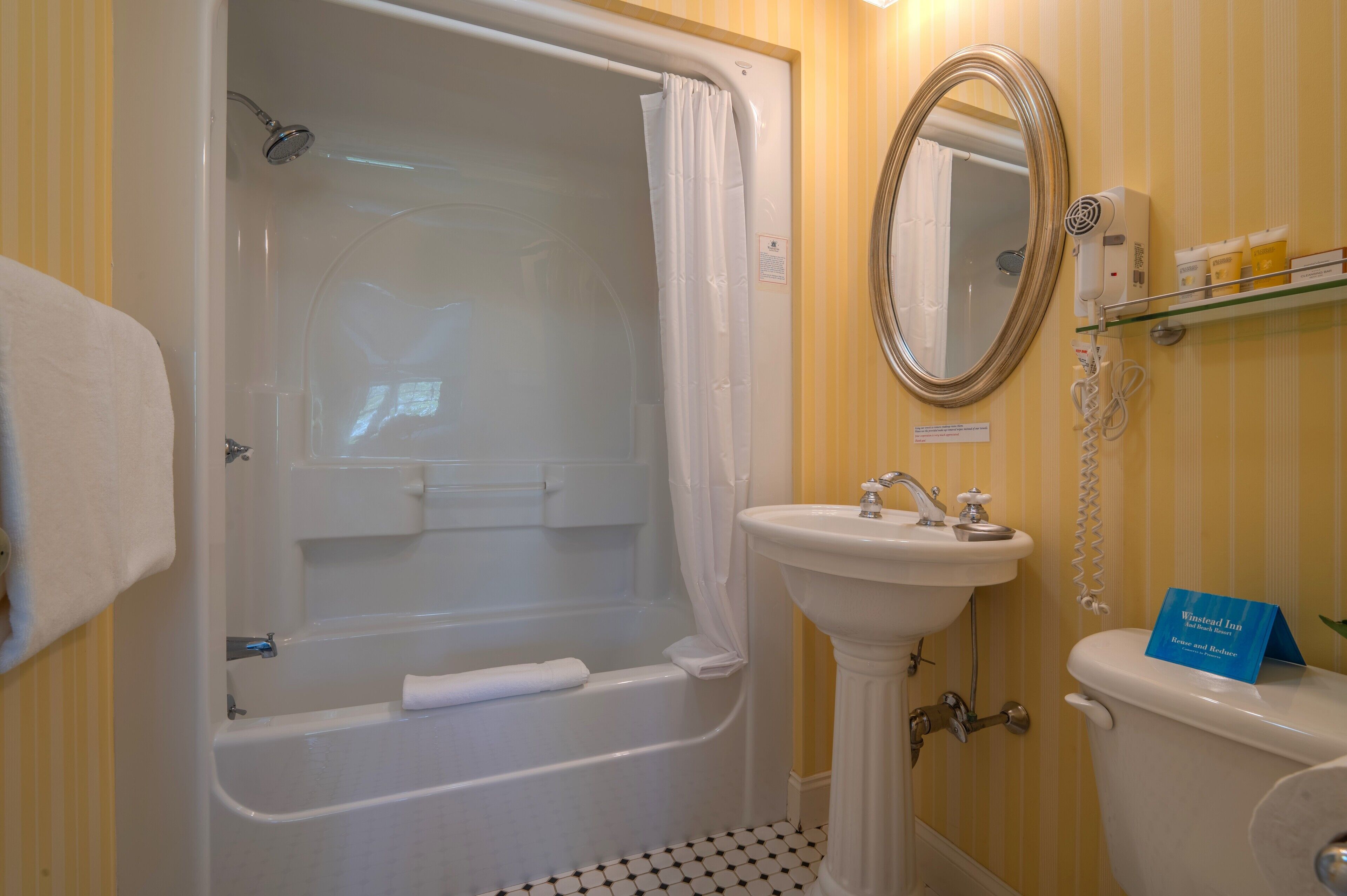 Un baño con bañera, lavabo, inodoro, espejo y cortina de ducha.