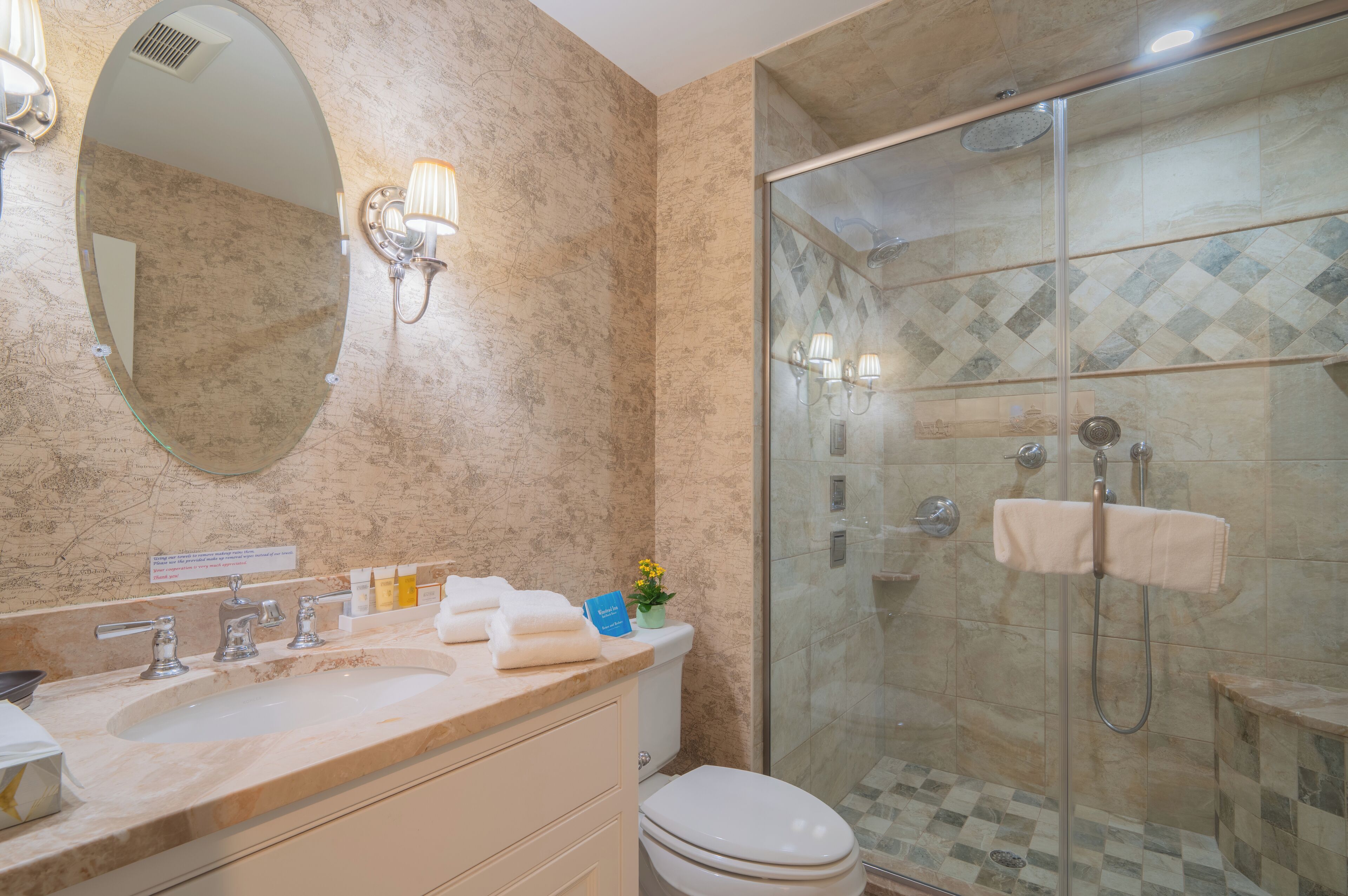 Une salle de bain avec un lavabo en marbre, une douche à parois de verre et des toilettes.