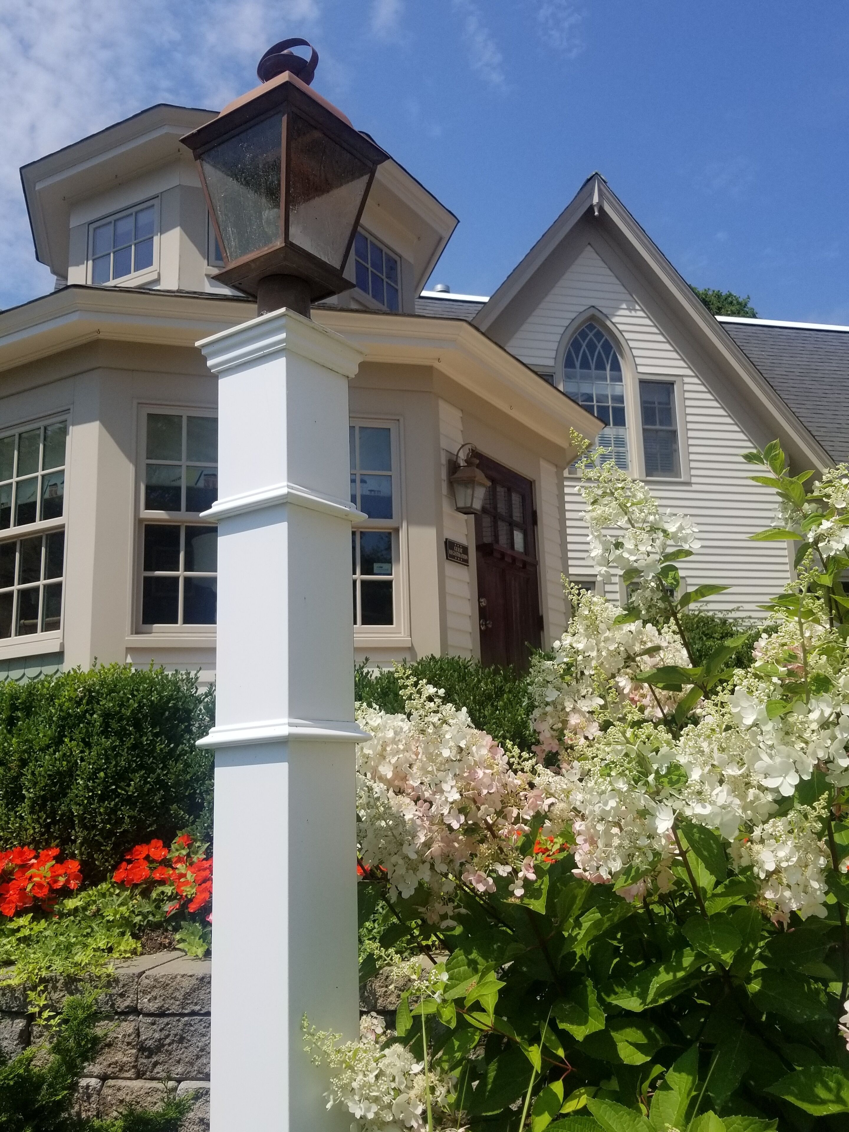 A white house with a prominent corner lantern, a front door, and a window with a decorative design.
