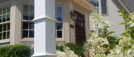 A white house with a prominent corner lantern, a front door, and a window with a decorative design.