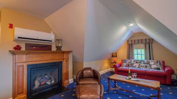 A cozy living room with a fireplace, leather armchair, and a red sofa.