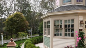 A corner building with a curved roof, large windows, and a well-maintained garden with various plants and flowers. - Winstead Inn (Harwich)