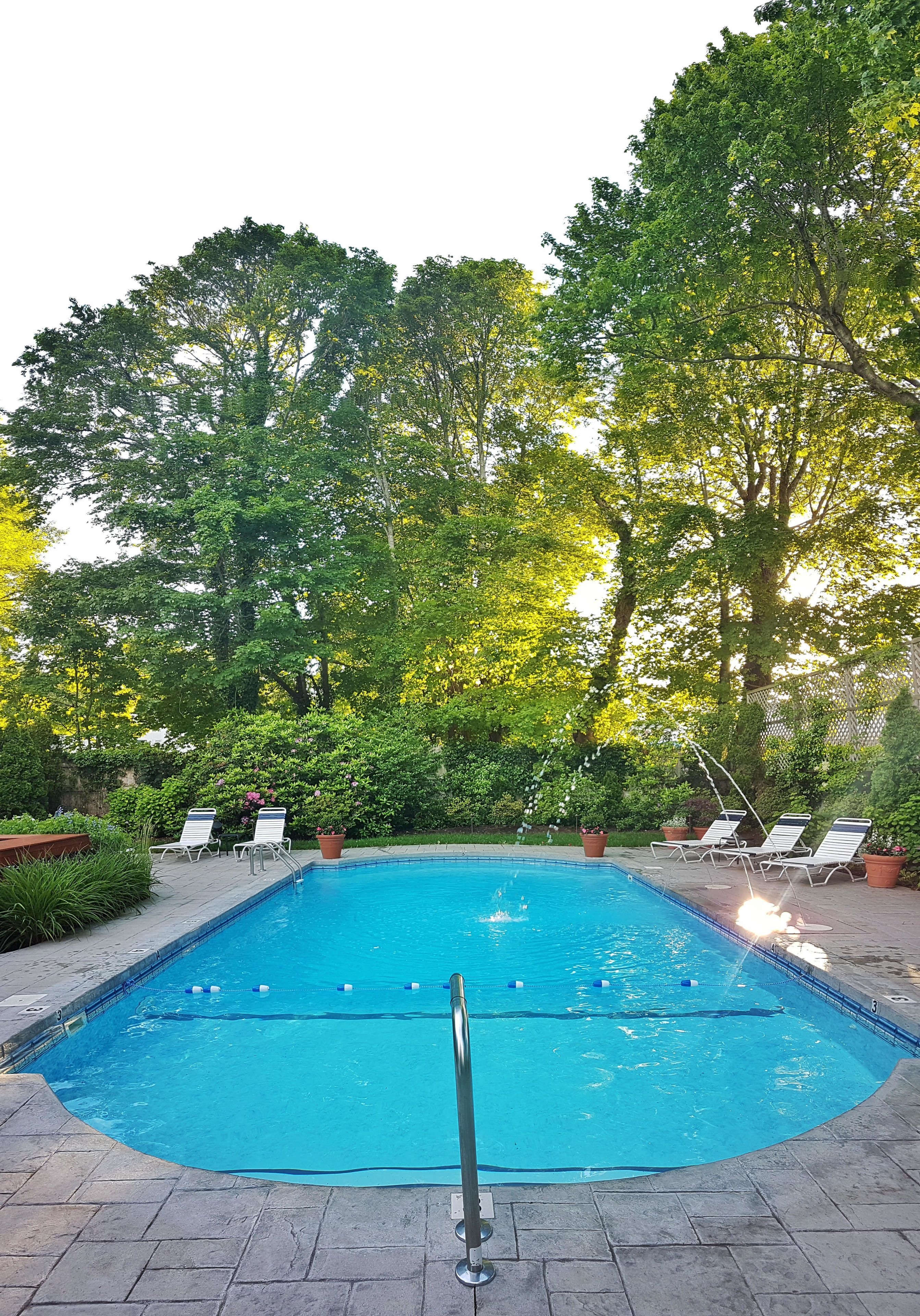 Piscina retangular com superfície de água azul e límpida, rodeada por um deck pavimentado.