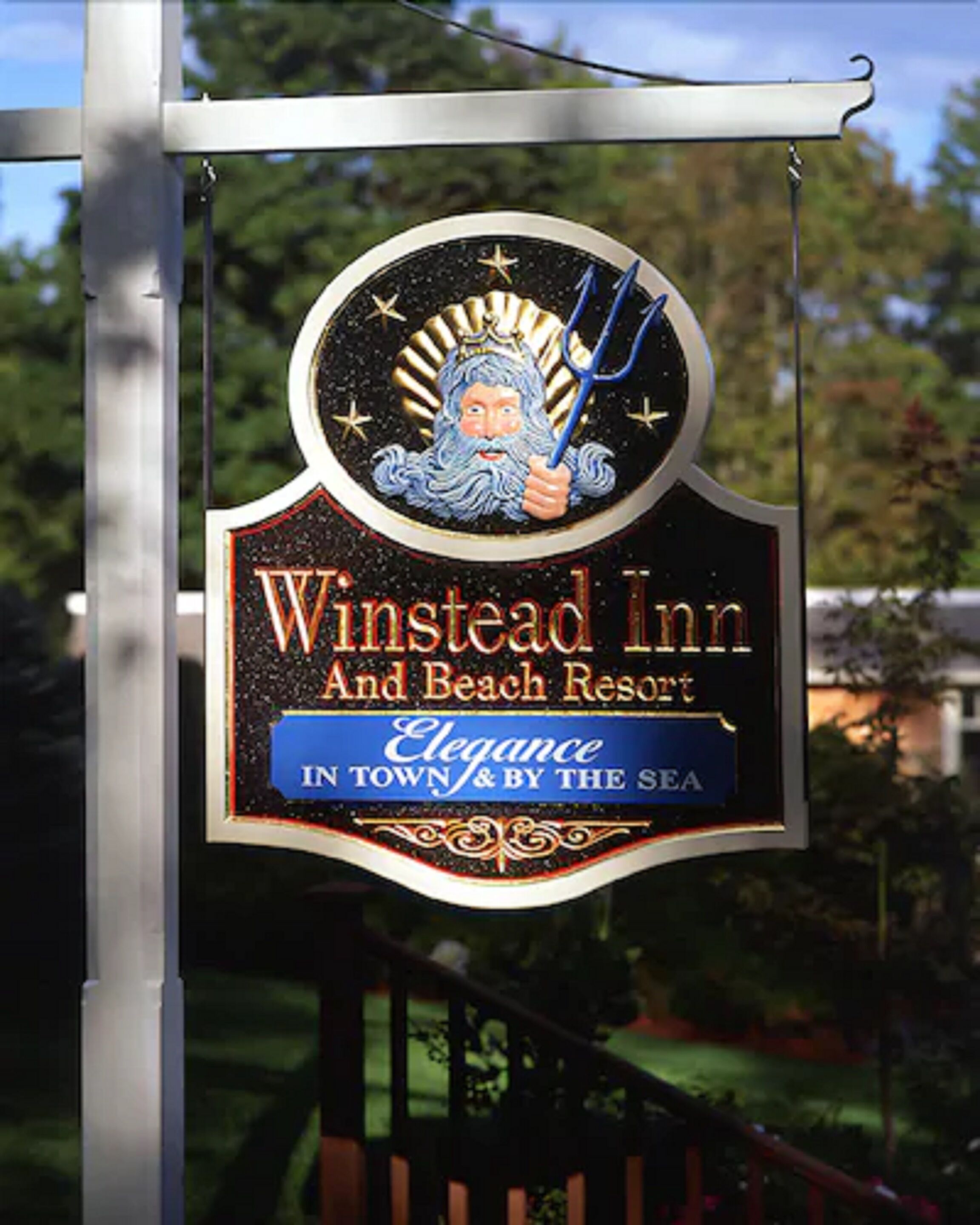 Placa do Winstead Inn e Beach Resort, com um logotipo mostrando uma figura segurando um tridente e estrelas, e o texto: 'Elegância na cidade e à beira-mar'.