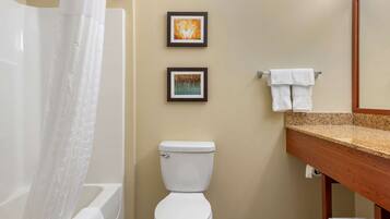A bathroom with a bathtub, toilet, and two framed pictures on the wall.