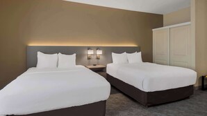 Une chambre d’hôtel avec deux lits, une table de chevet et une armoire.