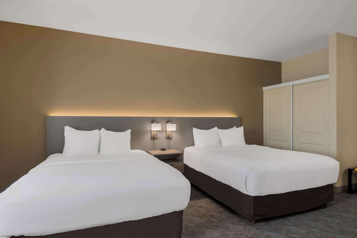A hotel room with two beds, a nightstand, and a wardrobe.