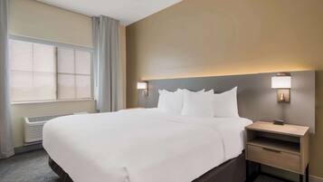 Quarto de hotel com uma cama grande, mesas de cabeceira e uma janela com cortinas.