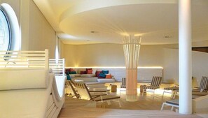 A spacious living area with a curved ceiling, a large window, and a seating arrangement including a sofa and chairs.