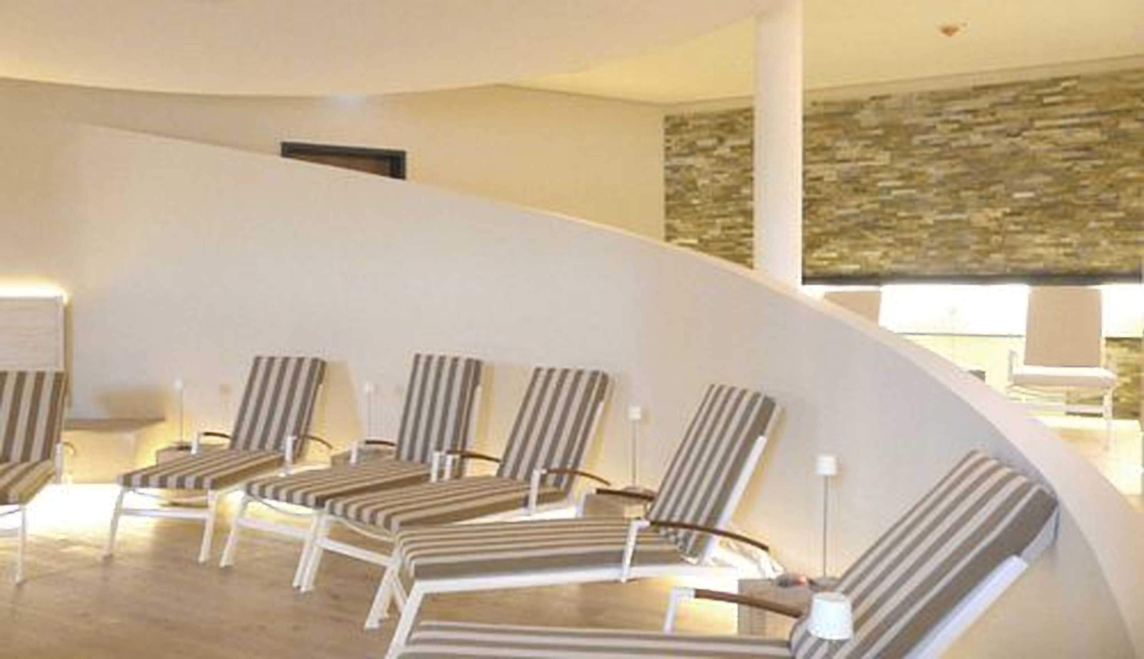 A curved seating area with striped chairs and a stone wall in the background.