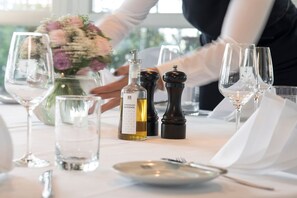 A table set with wine glasses, a bottle of olive oil, and salt and pepper shakers.