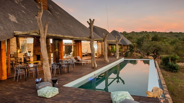A poolside area with lounge chairs and a dining setup. - Tala Game Reserve (Camperdown)