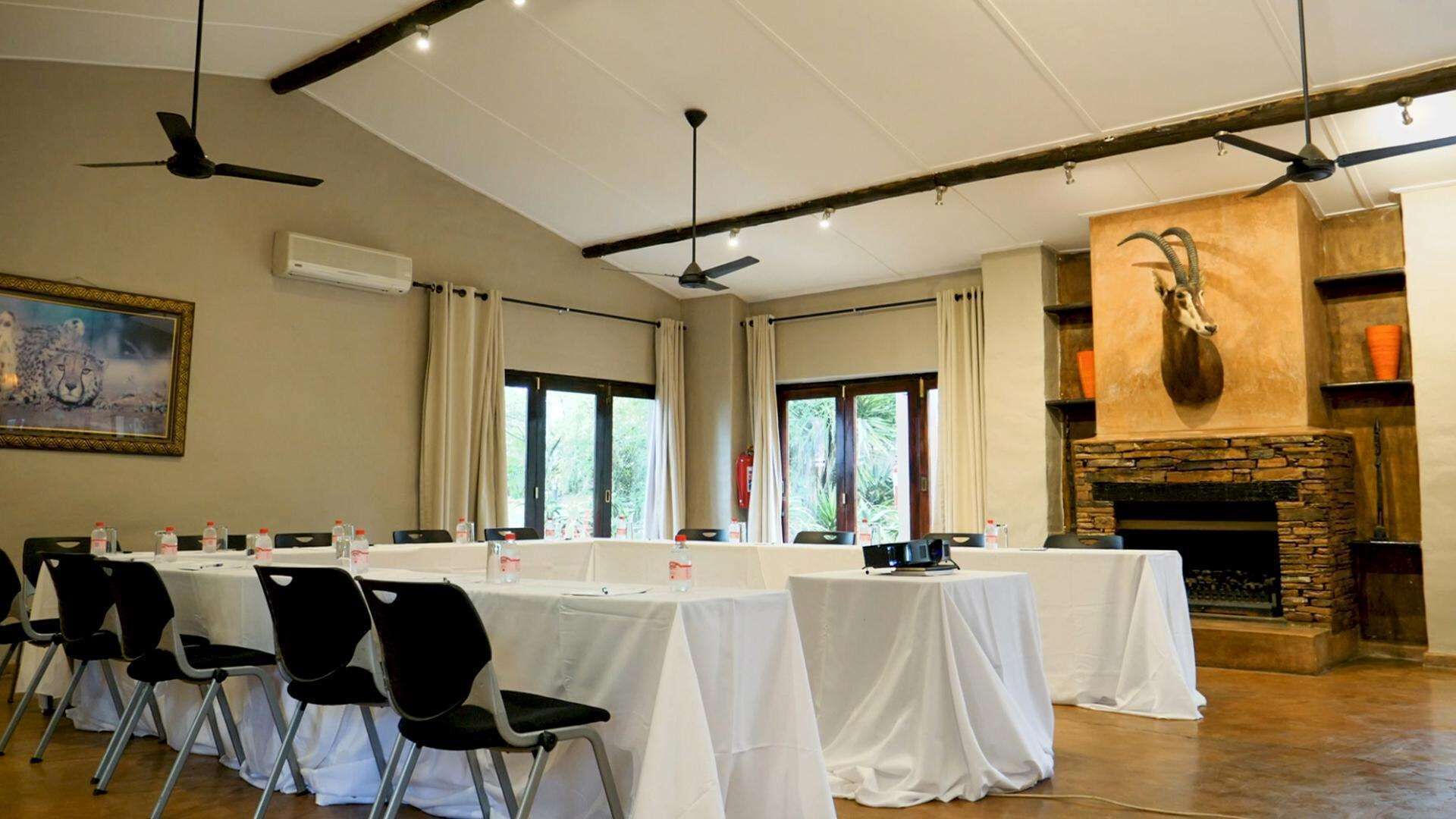 Una sala conferenze con tavoli e sedie, un camino e una ventola a soffitto.