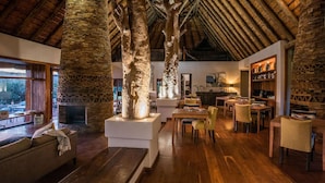 A rustic interior with exposed stone walls, wooden beams, and a cozy seating area with a fireplace. - Tala Game Reserve (Camperdown)
