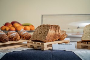 A variety of breads and pastries on wooden stands with a sign indicating a hotel location. - Blu Residence (Casarano)