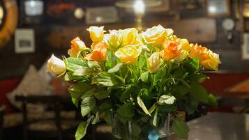A vase with yellow and white roses on a table in a dimly lit room with a hanging light fixture.