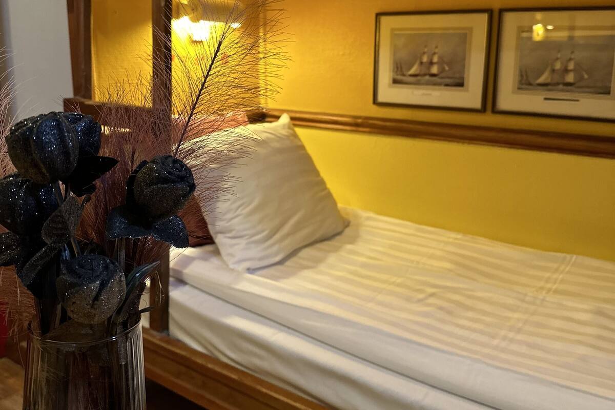 A bunk bed with a wooden headboard, a bedside table with a vase of flowers, and framed pictures on the wall.