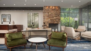 A modern living room with a stone fireplace, a large window with a view of greenery, and a round coffee table.