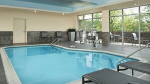 An indoor swimming pool with clear water, a lifeguard chair, and a sunshade.