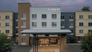 A multi-story hotel with a modern facade, a covered entrance, and a landscaped area with potted plants.