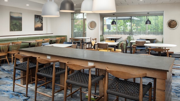 A modern dining area with a long counter, multiple seating options, and pendant lighting.