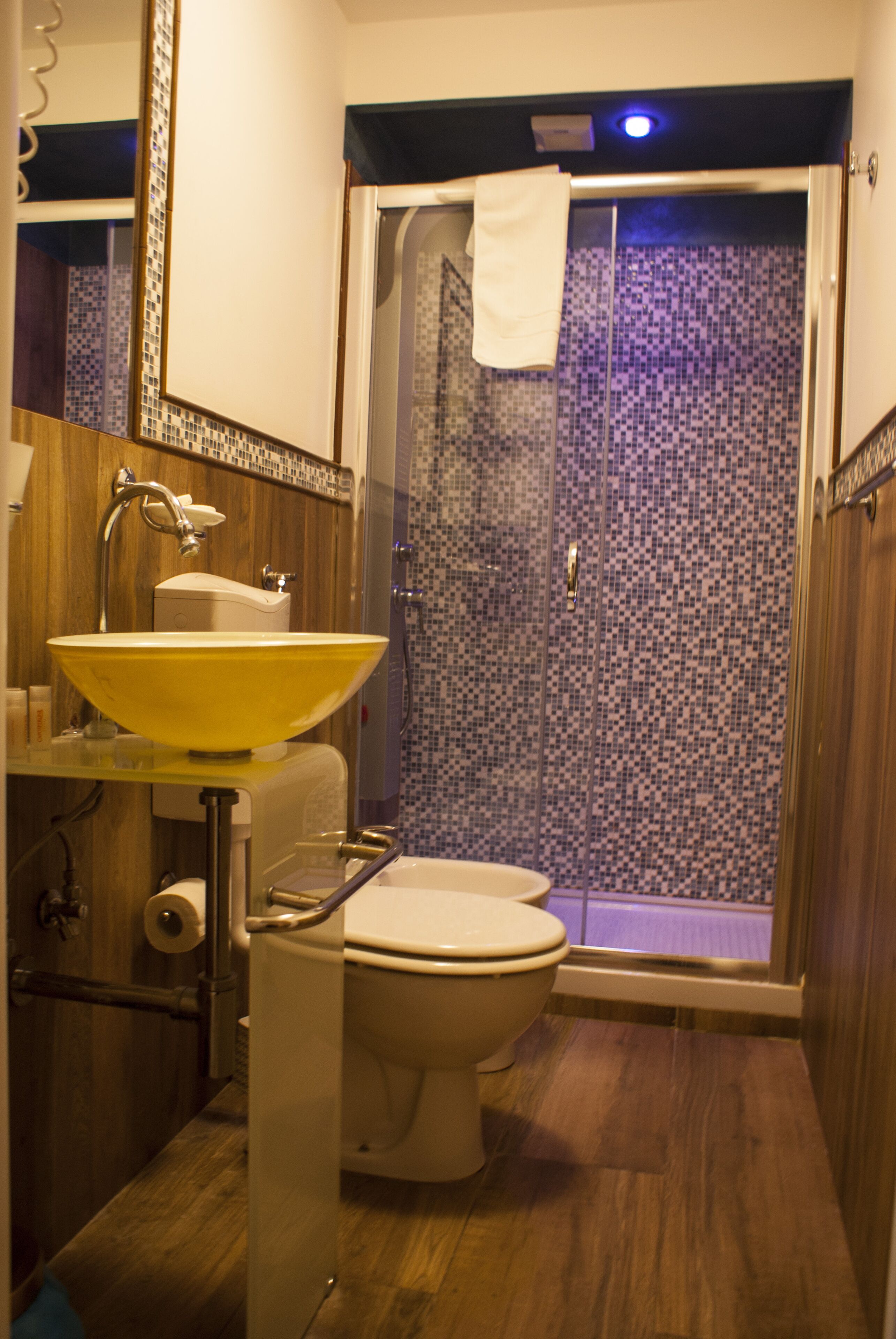 A bathroom with a yellow sink, a toilet, and a glass-enclosed shower.