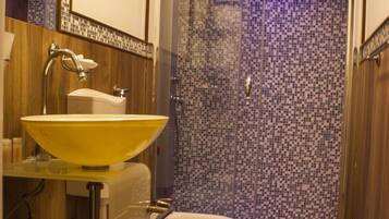 A bathroom with a yellow sink, a toilet, and a glass-enclosed shower.