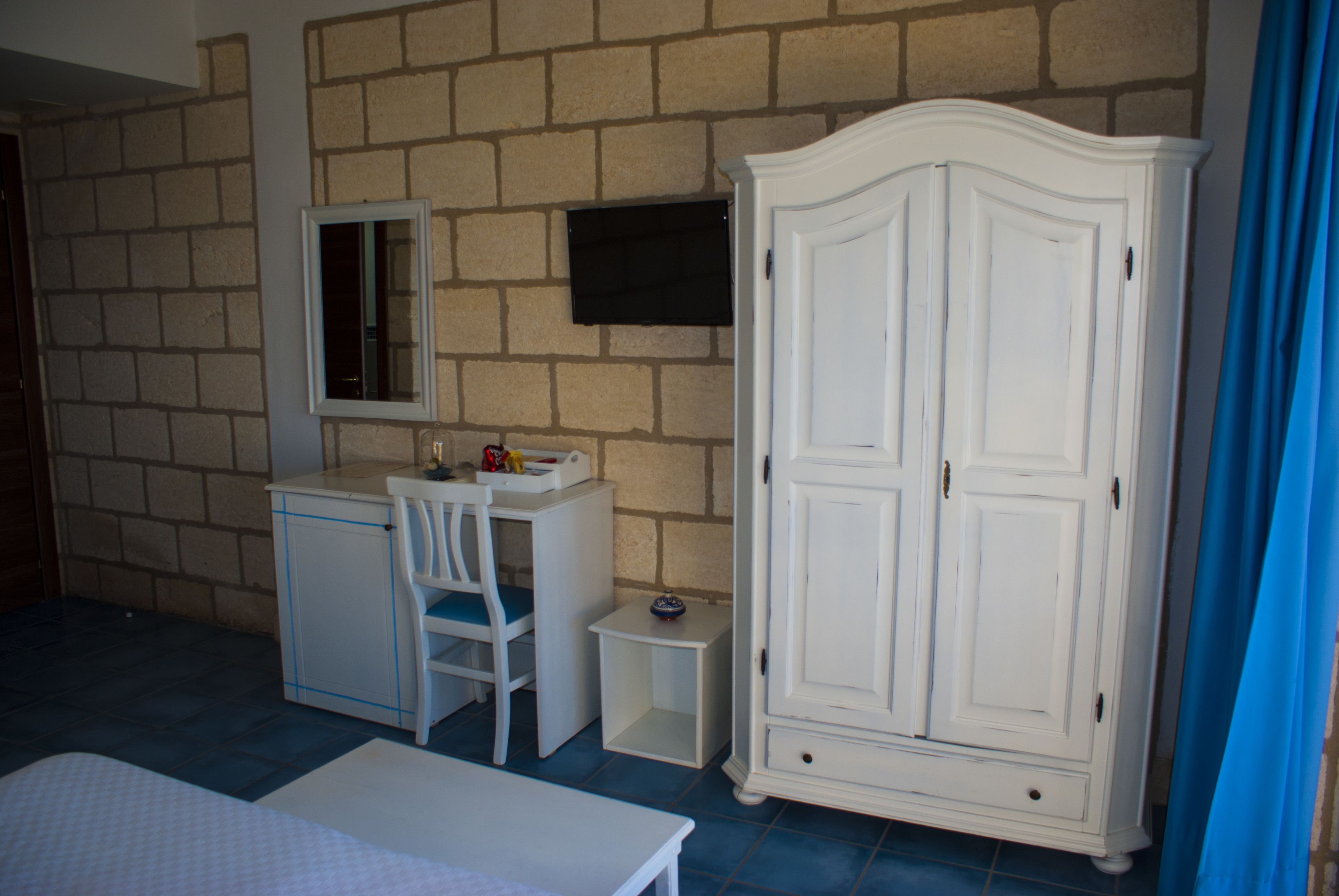 Une chambre à coucher comprenant un lit, un bureau avec une chaise, une armoire et une petite table.
