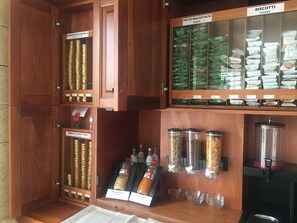 A bakery display with labeled jars of biscotti, cookies, and various jams and spreads.