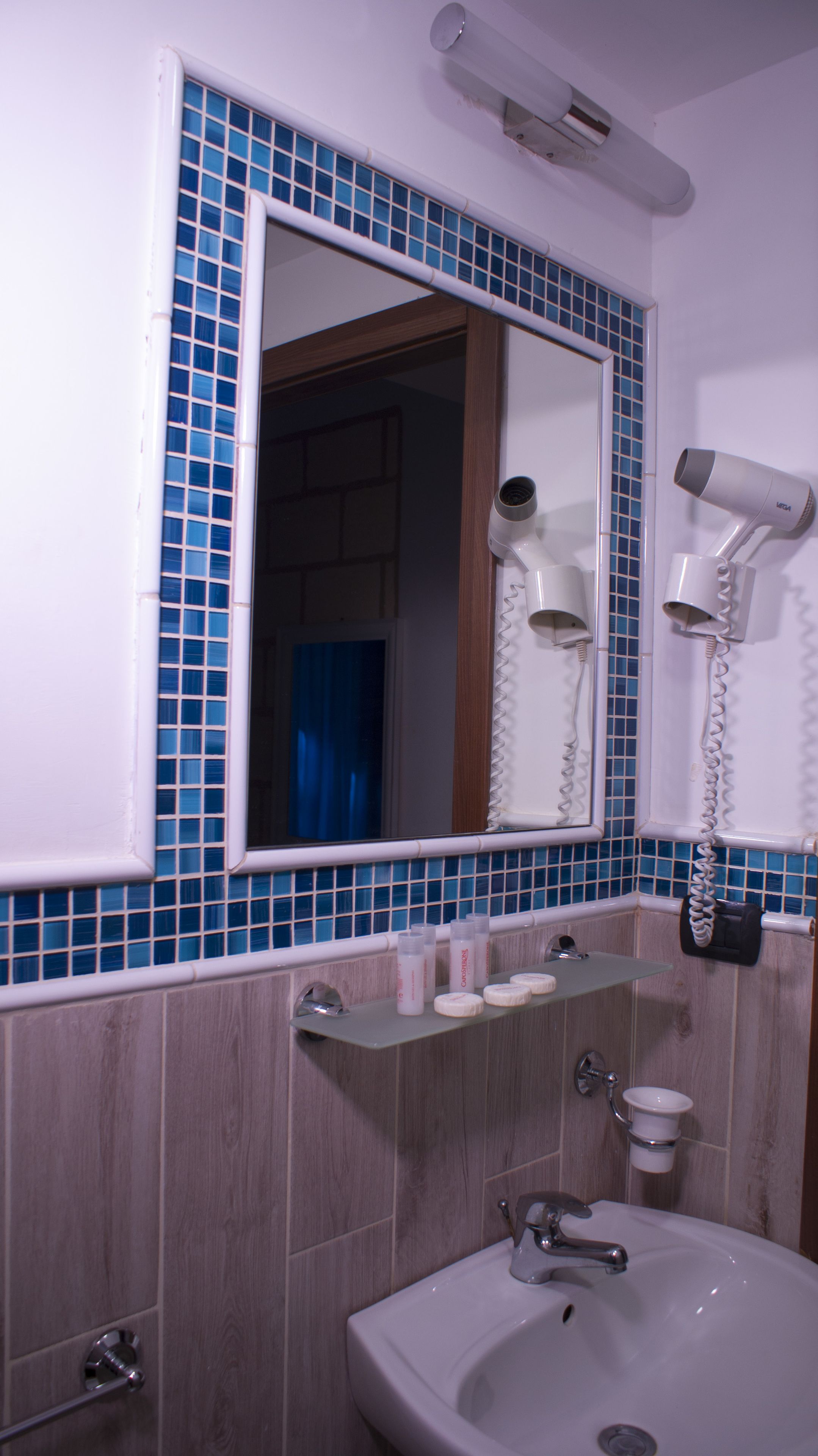 Un baño con lavamanos, espejo y secadores de pelo.