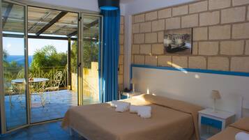 Habitación de hotel con cama, mesita de noche, silla y mesa, con vistas al exterior.
