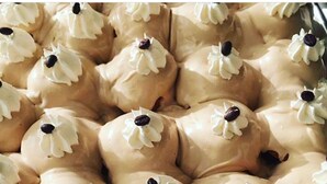 Primer plano de pasteles redondos con crema blanca encima y un centro oscuro, dispuestos en un patrón de cuadrícula.