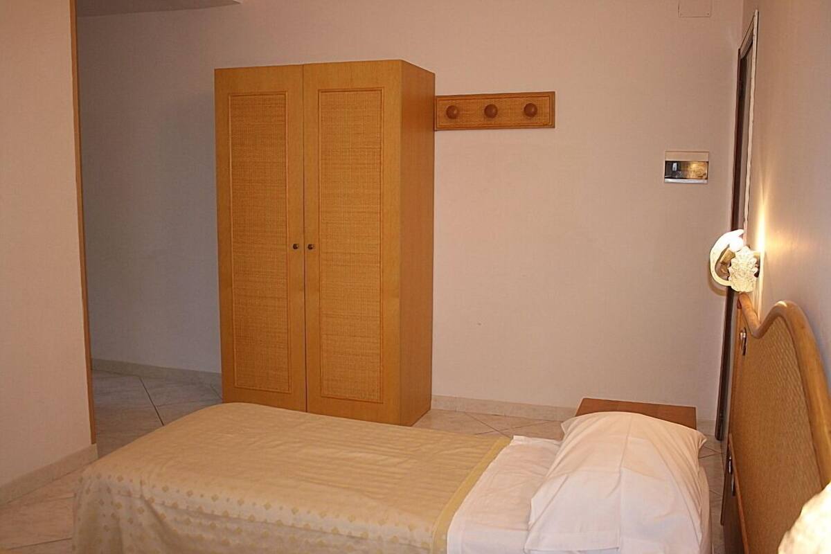 A bedroom with a bed, a wardrobe, and a bedside table with a lamp.