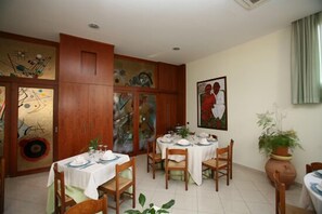 A dining area with wooden cabinets, a painting on the wall, and a potted plant.
