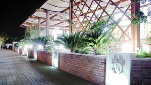 Un pasaje cubierto con paredes de ladrillo y plantas en macetas, que conduce a la entrada de un edificio.