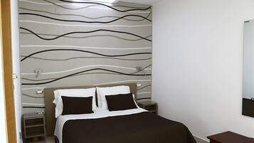 Una camera da letto con un letto, comodini, uno specchio e una parete con motivo ondulato.