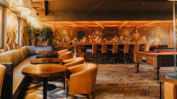 A bar area with wooden furniture, a billiards table, and a mural of people playing pool. - Kinlay Hostel Galway (Galway)
