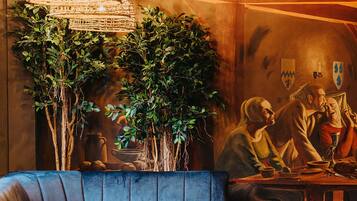 A cozy restaurant interior with a curved seating area, wooden tables, and a large hanging light fixture.