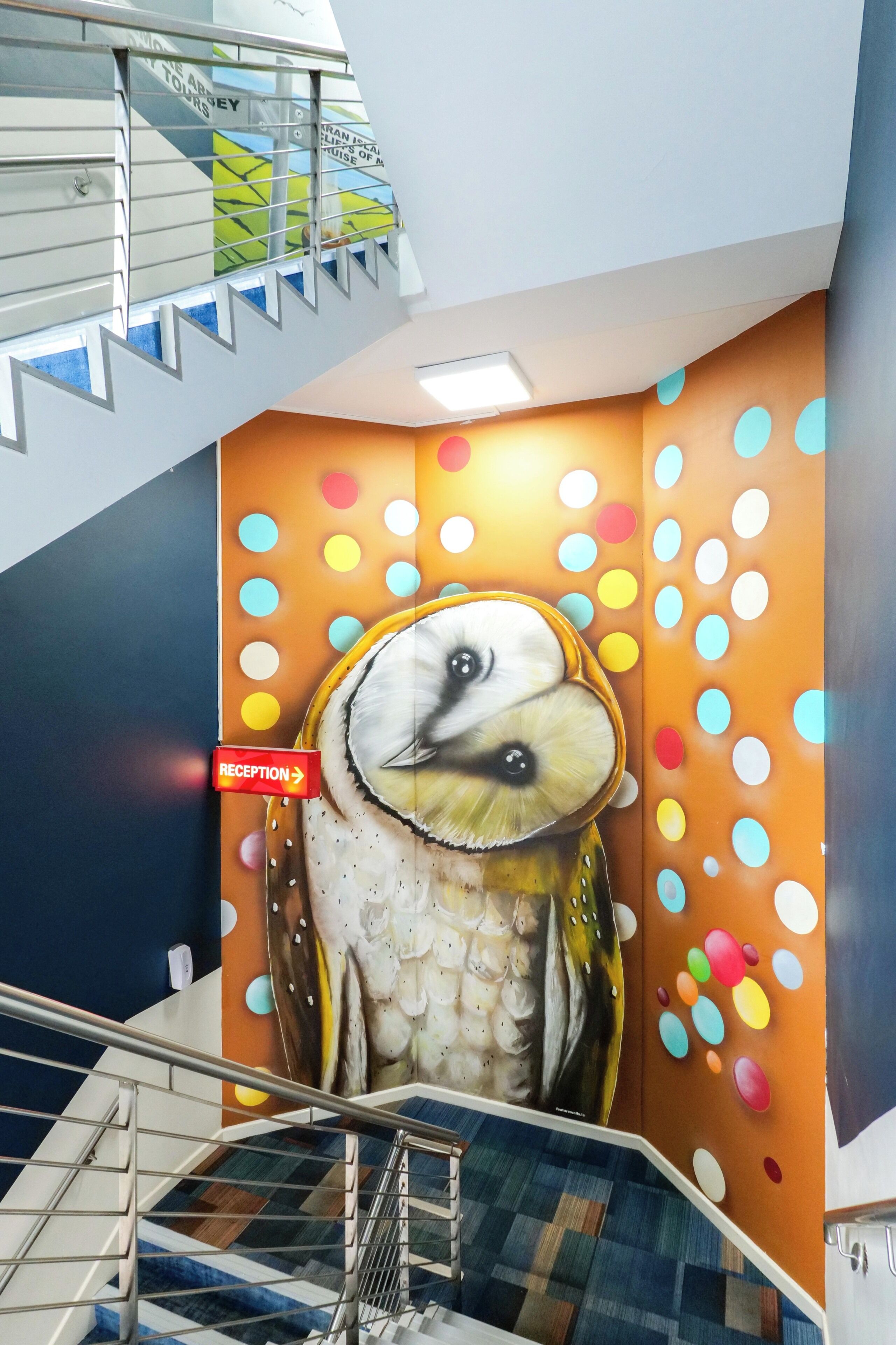 A staircase with a mural of an owl and a reception sign.
