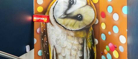 A staircase with a mural of an owl and a reception sign.