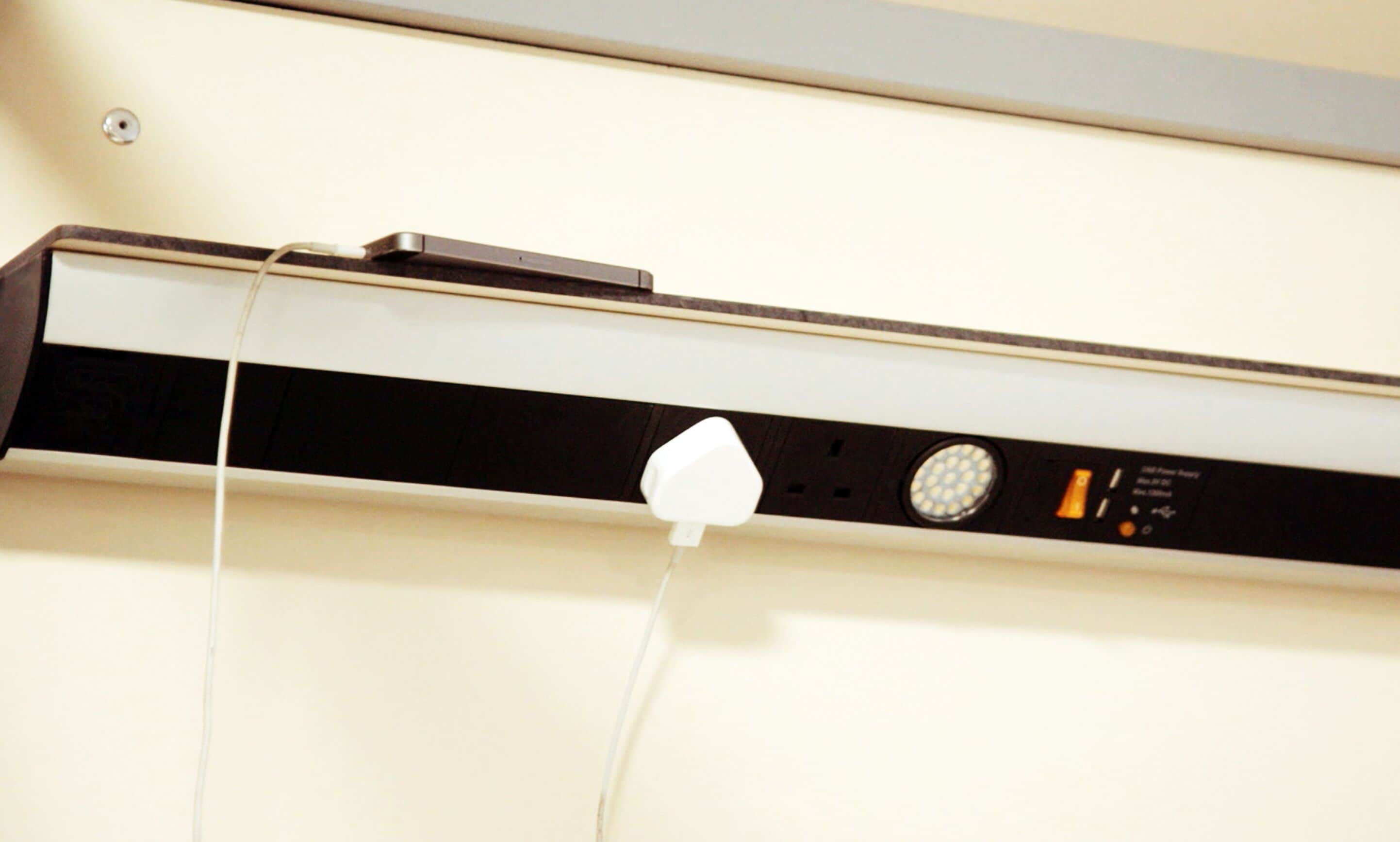 A wall-mounted device with a power cord plugged in.
