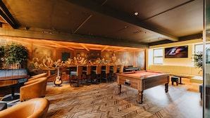 A billiards room with a pool table, chairs, a guitar, and a mural. - Kinlay Hostel Galway (Galway)